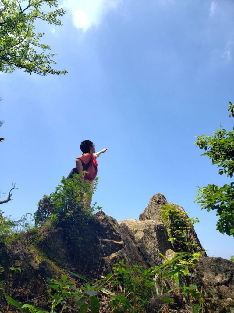 男性が山の頂で空に向かって手を挙げている